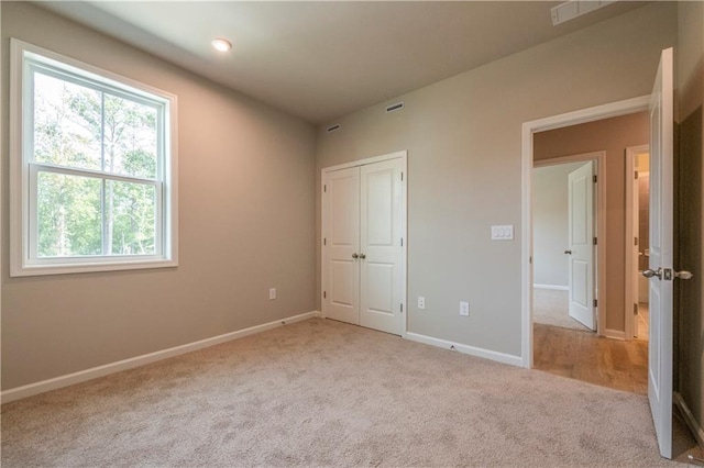 unfurnished bedroom with light colored carpet and a closet