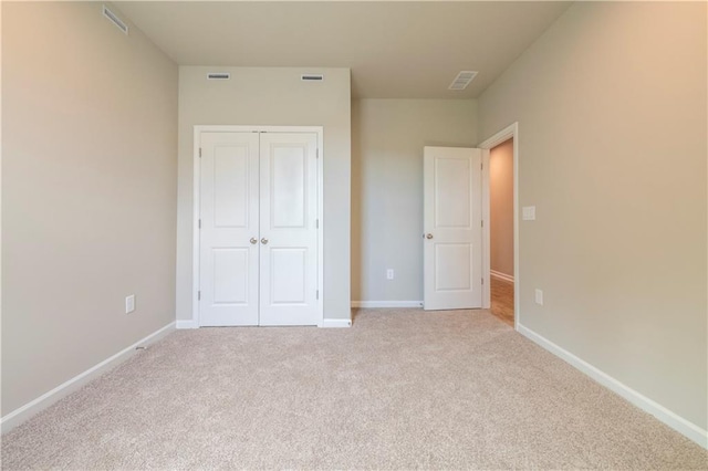 unfurnished bedroom with light colored carpet and a closet