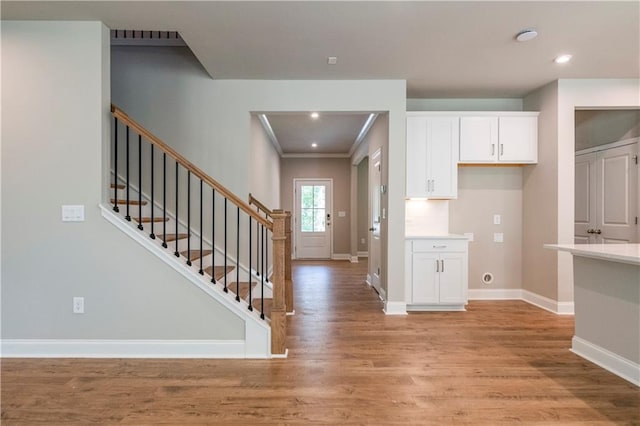 interior space featuring white cabinets, light wood-type flooring, and ornamental molding