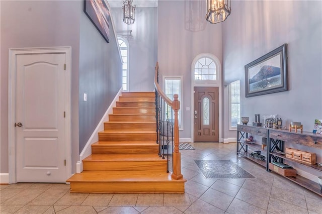 foyer featuring a towering ceiling, a chandelier, and light tile patterned floors