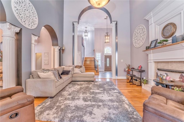 living room featuring ornate columns, light hardwood / wood-style floors, and a towering ceiling