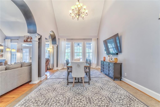 dining room with an inviting chandelier, light wood-type flooring, ornate columns, and high vaulted ceiling