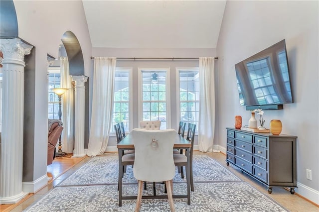 dining space with light wood-type flooring, ornate columns, and high vaulted ceiling