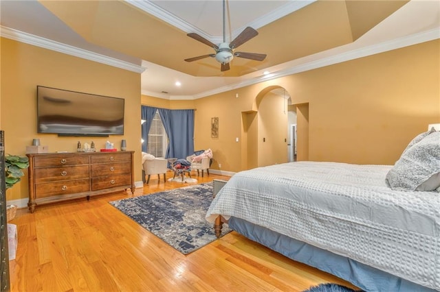 bedroom with wood-type flooring, ornamental molding, a tray ceiling, and ceiling fan