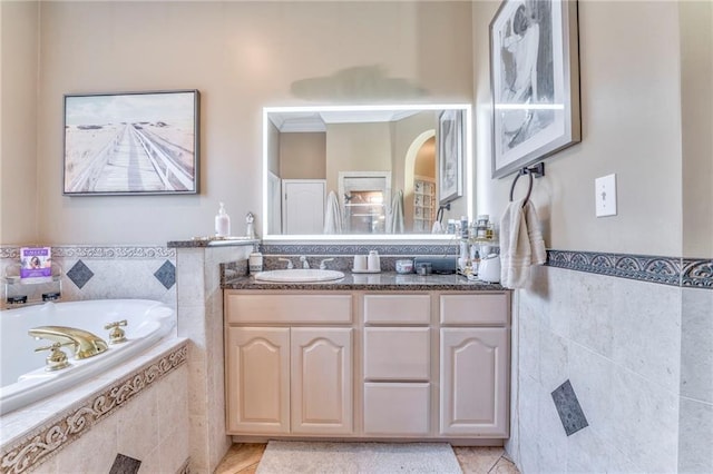 bathroom featuring tiled tub, vanity, and tile patterned flooring