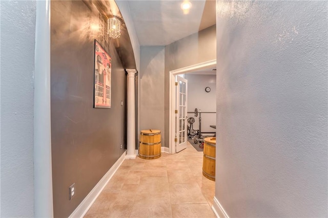 corridor featuring decorative columns and light tile patterned floors