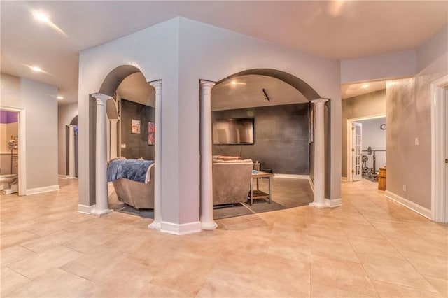 hallway featuring decorative columns and light tile patterned floors