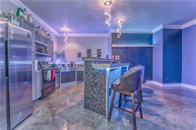 kitchen with appliances with stainless steel finishes, a kitchen island, and crown molding