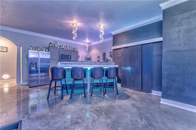 interior space featuring stainless steel appliances, ornamental molding, kitchen peninsula, and a breakfast bar