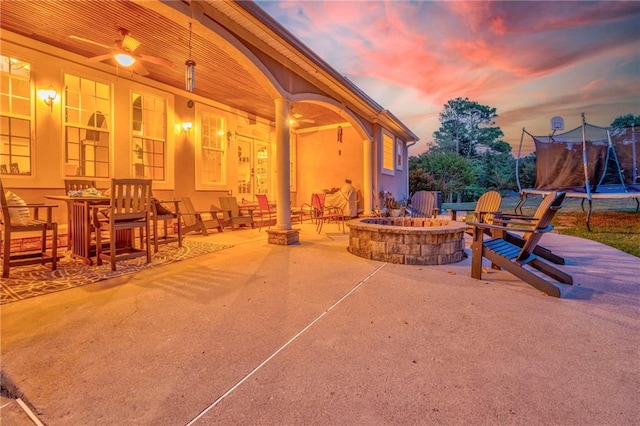 patio terrace at dusk featuring a trampoline and an outdoor fire pit