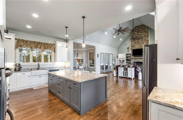 kitchen with gray cabinetry, white cabinetry, a center island, a stone fireplace, and pendant lighting