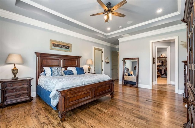 bedroom with a raised ceiling, ceiling fan, dark wood-type flooring, and ornamental molding