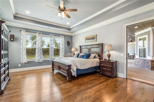 bedroom with ceiling fan, a raised ceiling, ornamental molding, and dark wood-type flooring