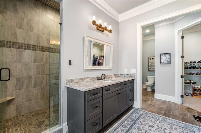 bathroom featuring vanity, toilet, a shower with shower door, and crown molding