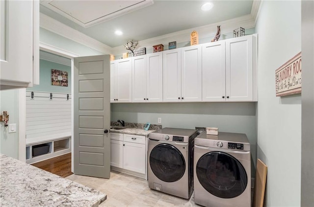 laundry room featuring washing machine and clothes dryer, crown molding, sink, and cabinets