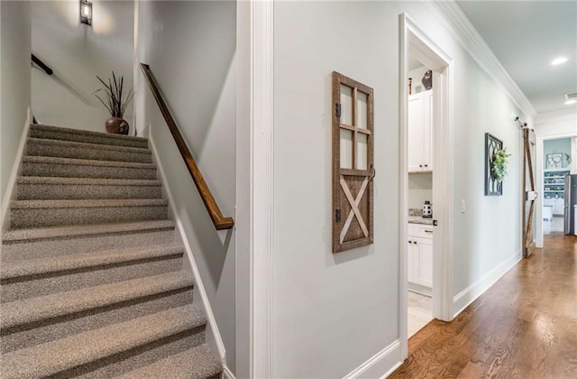 stairs featuring wood-type flooring and crown molding