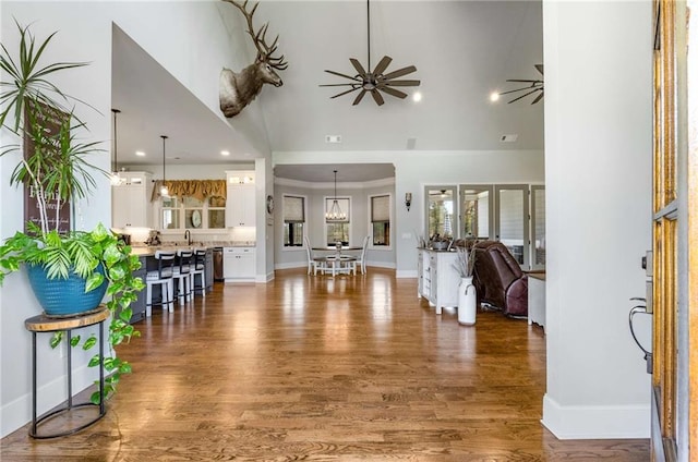 foyer with ceiling fan, sink, a towering ceiling, and dark wood-type flooring