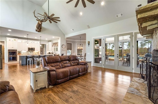 living room featuring wood-type flooring, high vaulted ceiling, and ceiling fan