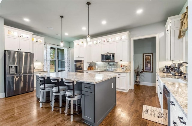 kitchen featuring appliances with stainless steel finishes, dark hardwood / wood-style flooring, pendant lighting, a center island, and white cabinetry