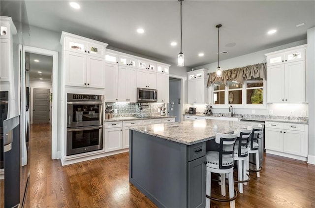 kitchen with a kitchen island, white cabinetry, stainless steel appliances, and dark wood-type flooring