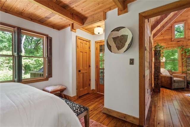 bedroom featuring beam ceiling, wood-type flooring, and wooden ceiling