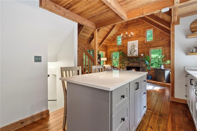 kitchen with wood walls, dark hardwood / wood-style floors, a fireplace, decorative light fixtures, and a kitchen island