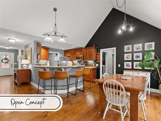 dining room with wood-type flooring, a notable chandelier, and high vaulted ceiling