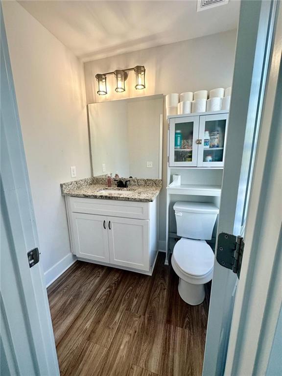 bathroom with hardwood / wood-style floors, toilet, and vanity