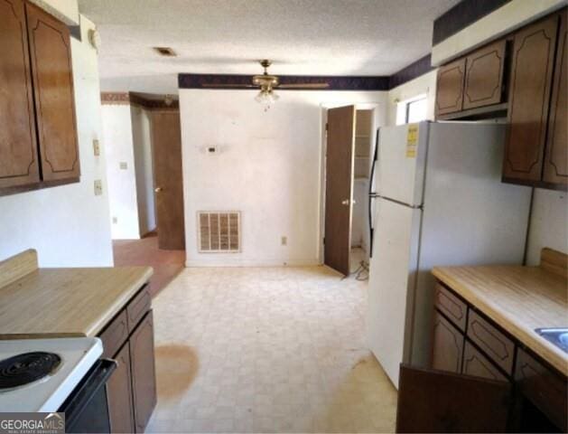 kitchen with light countertops, freestanding refrigerator, visible vents, and a textured ceiling