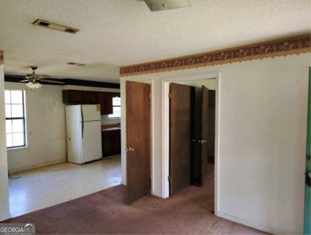 spare room with light carpet, visible vents, plenty of natural light, and a textured ceiling