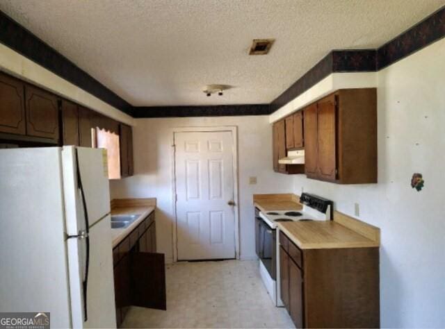 kitchen featuring light countertops, white appliances, light floors, and under cabinet range hood