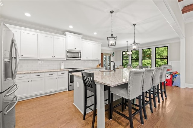 5821 Abbey View Ct, Clermont, GA 30527 - kitchen featuring appliances with stainless steel finishes, ornamental molding, decorative backsplash, a kitchen bar, and white cabinets