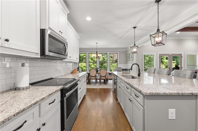 5821 Abbey View Ct, Clermont, GA 30527 - kitchen featuring appliances with stainless steel finishes, ornamental molding, white cabinetry, decorative backsplash, and french doors