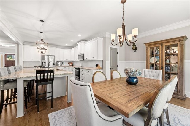5821 Abbey View Ct, Clermont, GA 30527 - dining space with a chandelier, crown molding, recessed lighting, wood finished floors, and a wainscoted wall