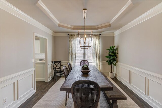 dining room with a decorative wall, crown molding, a raised ceiling, and dark wood-style flooring