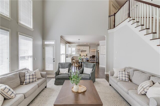 living room with stairs, wood finished floors, a wealth of natural light, and a chandelier