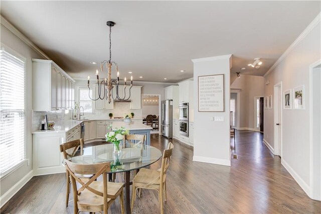 dining space with dark wood-style floors, baseboards, crown molding, and an inviting chandelier