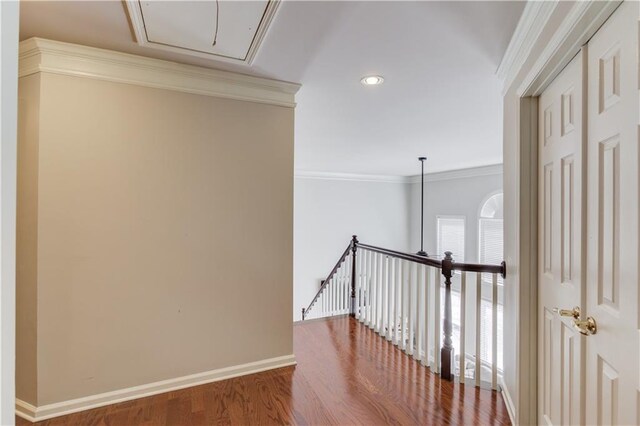 corridor featuring baseboards, attic access, wood finished floors, and crown molding