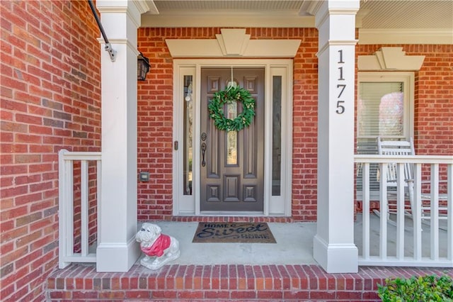 property entrance with brick siding and a porch