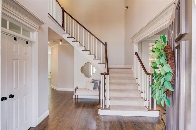 staircase with baseboards, a high ceiling, and wood finished floors