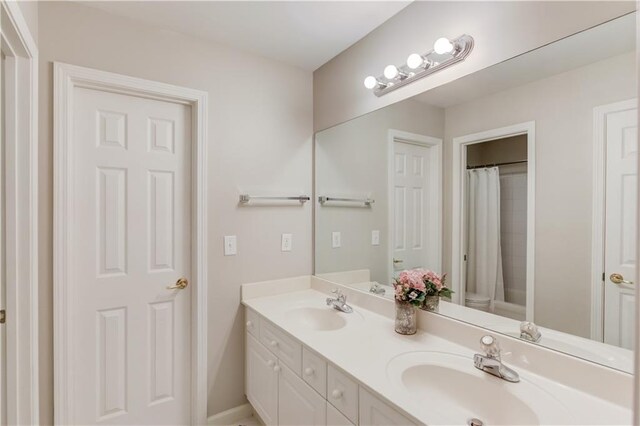 full bathroom with a shower with shower curtain, double vanity, toilet, and a sink