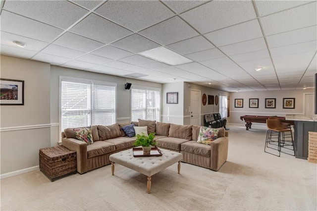 living area with a paneled ceiling, light carpet, and baseboards