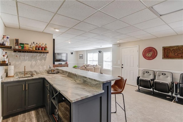 kitchen with a sink, light stone countertops, a kitchen breakfast bar, a peninsula, and open shelves