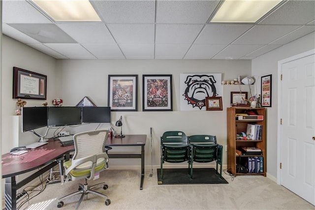 carpeted office space with baseboards and a paneled ceiling