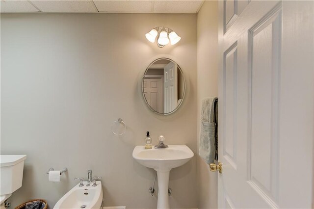 bathroom featuring toilet, a bidet, and a drop ceiling