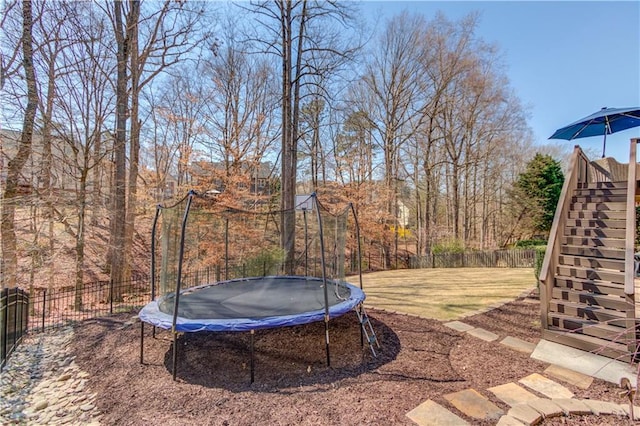 view of yard with stairway, a trampoline, and fence