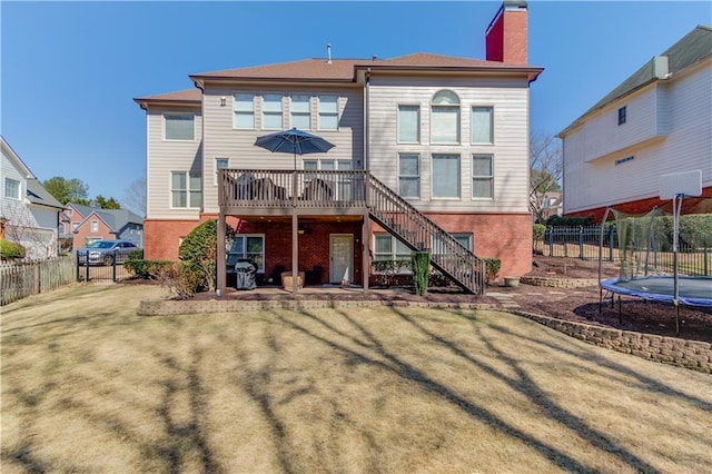 back of property featuring stairway, a yard, a fenced backyard, a chimney, and a trampoline