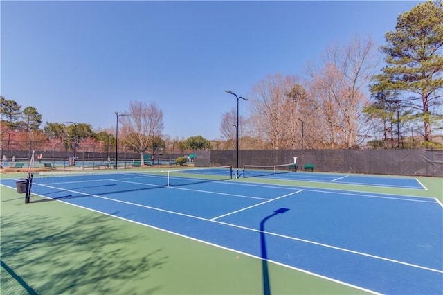 view of tennis court with community basketball court and fence