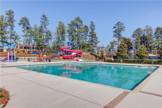 pool featuring a patio area, a water slide, and fence