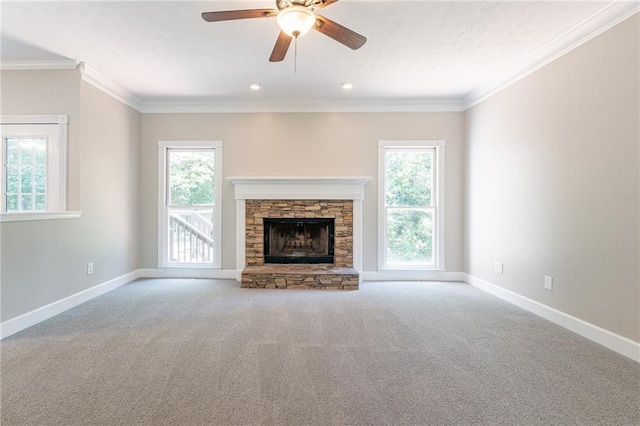 unfurnished living room with a stone fireplace, carpet flooring, crown molding, and ceiling fan